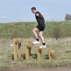 a man jumping over some wooden posts in the grass