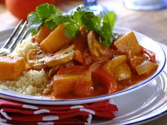 a white plate topped with rice and meat next to a red napkin on top of a wooden table