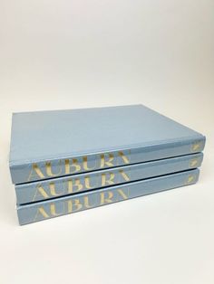 three blue books stacked on top of each other in front of a white background with gold lettering