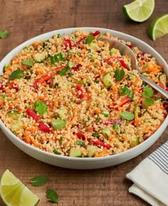 a bowl filled with rice and vegetables next to sliced limes