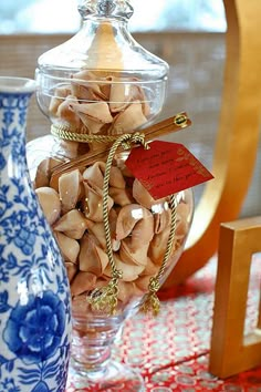 a glass jar filled with nuts sitting on top of a table next to two vases