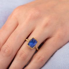 The faceted surface of this exceptional Tanzanite glows with a vibrant, powerful blue. This captivating, one-of-a-kind gemstone is set in a handmade gold setting accented with braided gold and granulated prongs. One of a Kind.Ready to ship in size 7. Please allow 1-2 weeks for any other size. Technical Details Metal: 18k yellow goldTanzanite: 4.56 cts. Ring face: 11.4 x 9.1mmBand width: 2mmHandmade in New YorkStyle # R-2540-TA Gold Emerald-cut Sapphire Ring With Gemstone Accents, Gold Sapphire Ring With Emerald Cut And Gemstone Accents, Emerald Cut Gold Sapphire Ring With Gemstone Accents, Yellow Gold Sapphire Ring With Emerald Cut, Unique Yellow Gold Sapphire Ring With Accent Stones, Exquisite Tanzanite Jewelry With Prong Setting, Gold Sapphire Jewelry With Accent Stones, Elegant Handmade Yellow Gold Sapphire Ring, Exquisite Sapphire Ring With Gemstone Accents