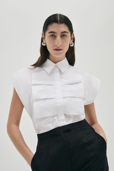 This luxe sleeveless shirt in 100% Cotton boasts a confident silhouette with wide shoulders, and front ruffle detail. The style has a concealed button front opening and is available in Ice Blue or White colour. Colour: White Fit: Loose fit silhouette. Model is wearing a Size AU 8 White Shirt Details, White Shirt Designs, Luxury White Top With Contrast Collar, Exaggerated Collar Shirt, Luxury Button-up Tops With Details, Modern White Button-up Top, Shirt Collar Design, Sleeveless Button Up Shirt, Deconstructed White Shirt