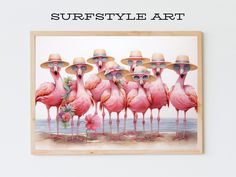 a group of pink flamingos wearing straw hats and standing in front of the ocean