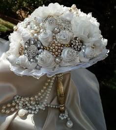 the bridal bouquet is adorned with pearls and brooches, as well as flowers