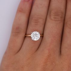 a woman's hand with a diamond ring on top of her finger, showing the center stone