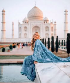 a woman is posing for a photo in front of the tajwak tower