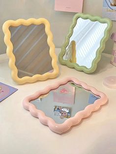 three different shaped mirrors sitting on top of a white table next to cards and pens