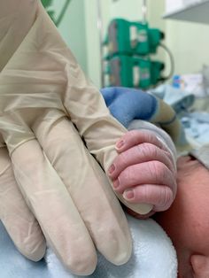 a newborn baby is being held in an inclosure with gloves on it's hands