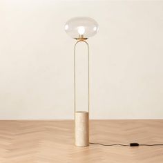 a floor lamp with a round glass shade on it's base and an electric cord plugged in