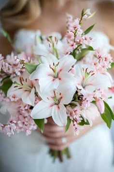 a bride holding a bouquet of white and pink flowers