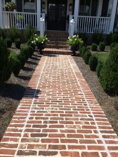 a brick walkway leading to a white house