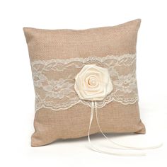 a pillow with a flower on it and lace around the edge, sitting on a white surface