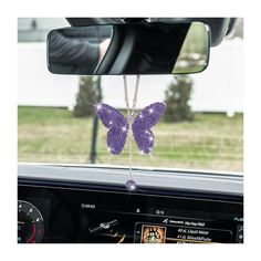 a purple butterfly hanging from the side of a car window in front of a mirror