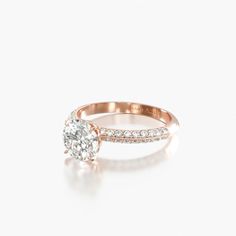 a rose gold engagement ring with diamonds on the band and an oval cut diamond in the center