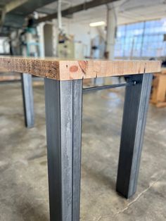 a wooden table with metal legs in a warehouse or office building, ready to be used as a dining room table