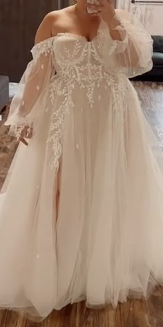 a woman in a wedding dress taking a selfie with her cell phone while standing on the floor