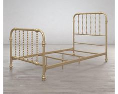 a gold metal bed frame with beads on the headboard and foot board, in an empty room