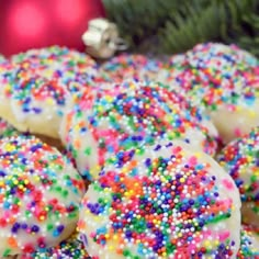 sprinkle covered cookies sitting on top of a plate next to a christmas tree