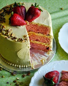 there is a cake that has been cut into pieces and served on plates with strawberries