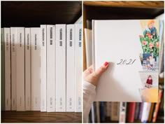 a person holding up a book in front of bookshelves with pictures on them