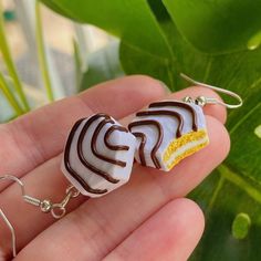 a pair of earrings with chocolate and lemon slices on them sitting in someone's hand