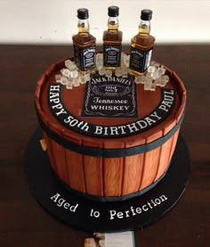 a birthday cake made to look like a barrel with three bottles of whiskey on top