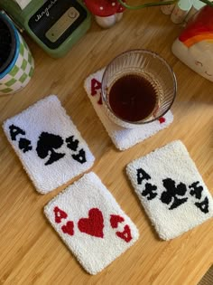 four coasters with playing cards on them and a cup of tea in the middle