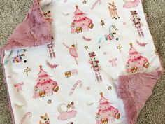 two baby blankets laying on the floor next to each other with pink and white designs