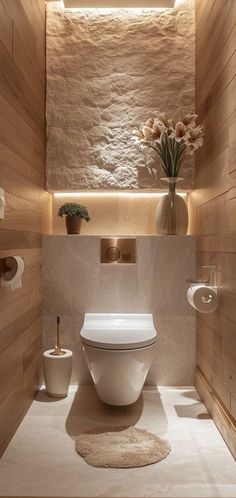 a toilet in a bathroom with wooden walls and flooring, along with two vases filled with flowers