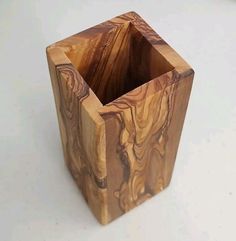 a small wooden vase sitting on top of a white table next to a pen holder