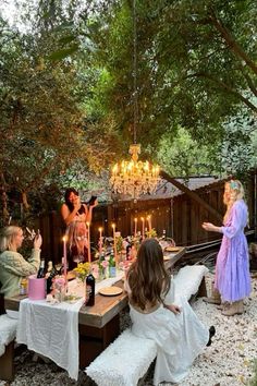 a group of people sitting around a table with candles on it