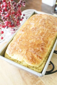 a loaf of bread sitting on top of a table next to a vase filled with berries