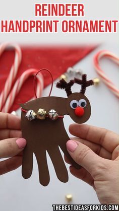 a handprinted reindeer ornament is being held in front of candy canes