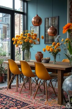 a dining room table with yellow chairs and vases filled with orange flowers on it