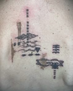 the back of a woman's neck with tattoos on her chest and other symbols