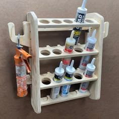 a shelf that has several bottles and glues on it, with an orange tool hanging from the top