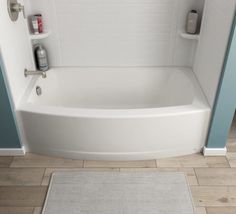 a white bath tub sitting inside of a bathroom next to a shower head and rug