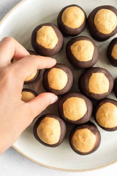 a person is picking up some chocolates from a plate