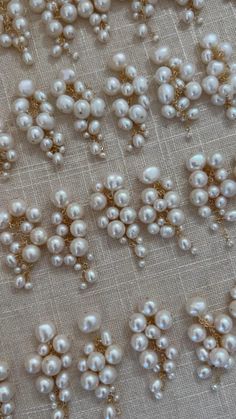 white pearls and gold beads are scattered on a beige fabric with golden sequins