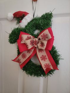 a christmas wreath hanging on the door with santa's hat in the back ground