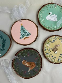 four hand painted wood slices with animals and trees on them, one is for christmas