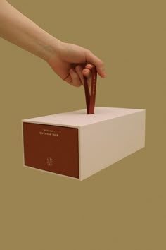 a hand is holding an empty box with a red ribbon in it and the other hand is reaching out