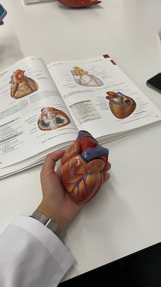 a person holding an open book while sitting at a table with medical equipment on it