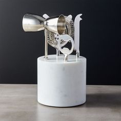 a white vase with a metal object on top of it