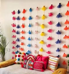 a bed with pillows and colorful decorations on the wall behind it is decorated with pom - poms