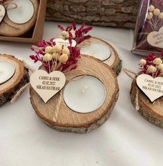 some candles are sitting on wood slices with flowers and hearts attached to them in the center