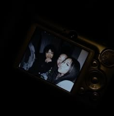 a person taking a photo with a cell phone in the dark while another person is holding a camera