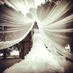 the bride and groom are walking down the aisle in their wedding dress with sun streaming through them