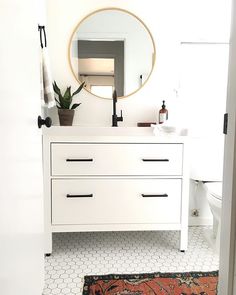 a bathroom with a white vanity, mirror and rug on the floor in front of it